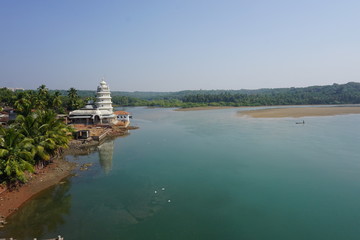 A white hindu temple on river bank in Kokan, Maharashtra, India. A scene in traditional village in...