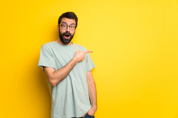 Man with beard and green shirt surprised and pointing side