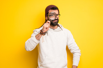 Hippie man with dreadlocks taking a magnifying glass and looking through it