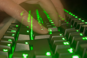 Typing fast on a green keyboard. Concept of hacking.
