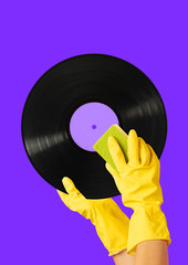 How to make a clean sound. Hands in yellow housewifely glove with the sponge cleaning black vinyl...