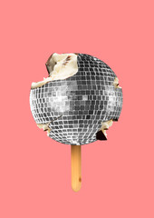 Ein musikalisches Eis. Eine silberne Discokugel als mit Sahne gefüllte und mit Schokolade überzogene Süßigkeiten auf Holzstab auf korallenrotem Hintergrund. Ein alternatives Essen. Modernes Design. Collage zeitgenössischer Kunst. © master1305