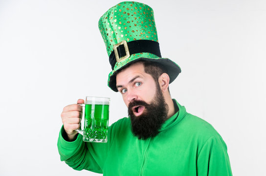 The raising of the green. Hipster in leprechaun hat holding beer mug. Celebrating saint patricks day in bar. Bearded man toasting to saint patricks day. Irish man with beard drinking green beer