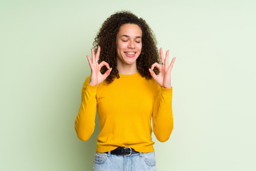 Dominican woman over isolated green background in zen pose