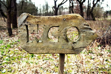 Wooden toilet sign in the forest.