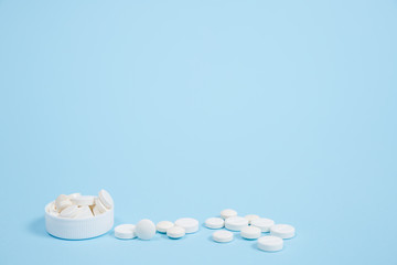 White medical pills on blue background.