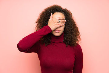 Dominican woman with turtleneck sweater covering eyes by hands