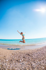 Fototapeta na wymiar Girl in a bathing suit jumping on the beach.
