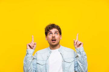 Blonde man over isolated yellow wall pointing with the index finger a great idea