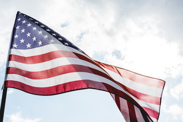 low angle view of national american flag with stars and stripes against sky with clouds