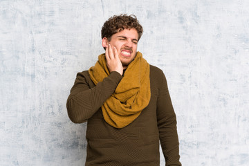 Blonde man over grunge wall with toothache