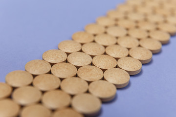Many brown pills on a purple background