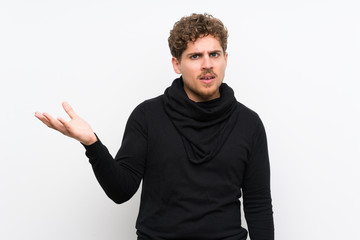 Blonde man over isolated white wall making doubts gesture