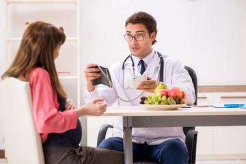 Pregnant woman visiting doctor discussing healthy diet