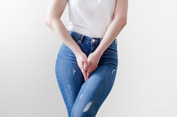 Young woman in jeans standing with her hands between legs