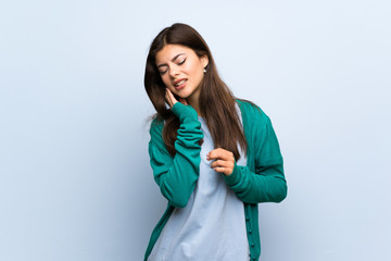 Teenager girl over blue wall with toothache