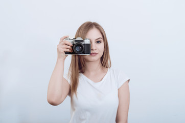 Attractive girl holding a vintage camera in her hands. Take a picture.