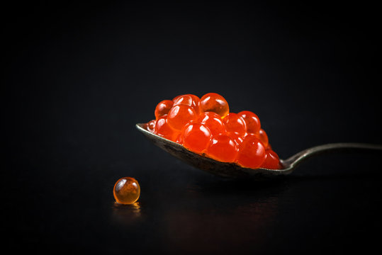 Spoon With Red Caviar On The Black Background