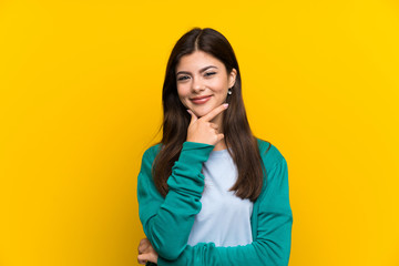 Teenager girl over yellow wall laughing