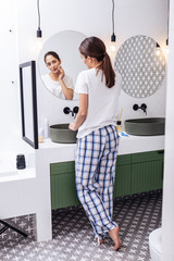 Dark-haired woman wearing squared pajama trousers removing makeup