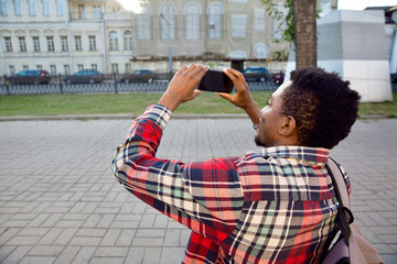 Closeup african man taking picture by phone on city street