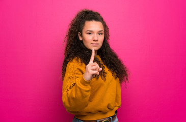 Teenager girl over pink wall frustrated and pointing to the front
