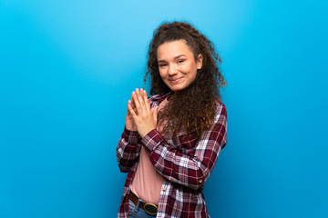 Teenager girl over blue wall scheming something