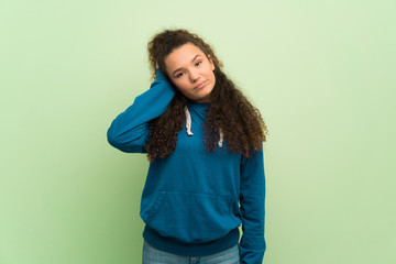 Teenager girl over green wall with an expression of frustration and not understanding