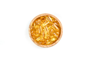 close up top view of fish oil capsules in wood bowl on white background.