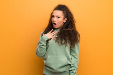 Teenager girl over ocher wall surprised and shocked while looking right