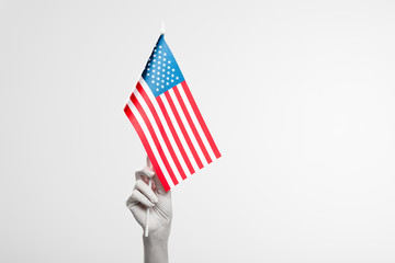 cropped view of female hand painted in white holding american flag isolated on grey