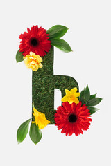 letter from cyrillic alphabet of green grass with bright red gerberas, yellow daffodils and leaves isolated on white