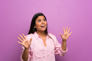 Young Colombian girl over purple wall nervous and scared