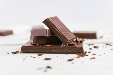 Chocolate bars on wooden table. Broken pieces of dark chocolate. Food background