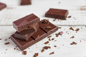 Chocolate bars on wooden table. Broken pieces of dark chocolate. Food background