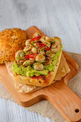 Smashed avocado, mushrooms and chili pepper whole grain sandwich. Decorated with thyme