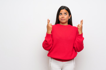 Young Colombian girl with red sweater with fingers crossing and wishing the best