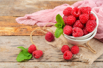 Red raspberries in bowl on grey wooden background.  Copy space