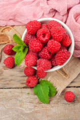 Red raspberries in bowl on grey wooden background.  Copy space