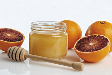 miele all'arancio in vaso con arance tagliate primo piano con cucchiaio