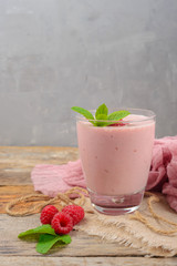 Glass of raspberry milk shake with berries on wooden background