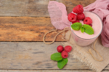 Glass of raspberry milk shake with berries on wooden background