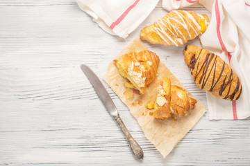 Fresh croissants with jam for breakfast on old white wooden background. Top view
