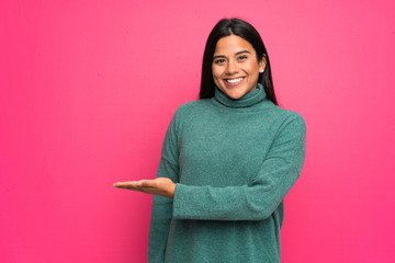 Young Colombian girl with green sweater presenting an idea while looking smiling towards