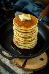 Pancakes with butter in the black pan. Decorated with tablecloth on a dark background