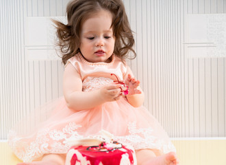 Baby girl holding a cherry from the cake