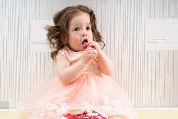 Baby girl eating sweet cake with her hands