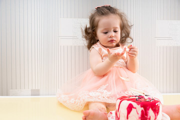 Cute baby girl tasting sweet cake