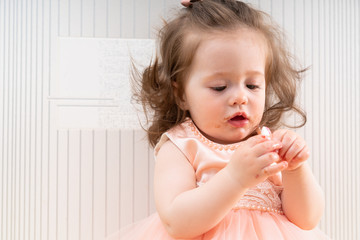 Pretty baby girl tasting cake with her fingers