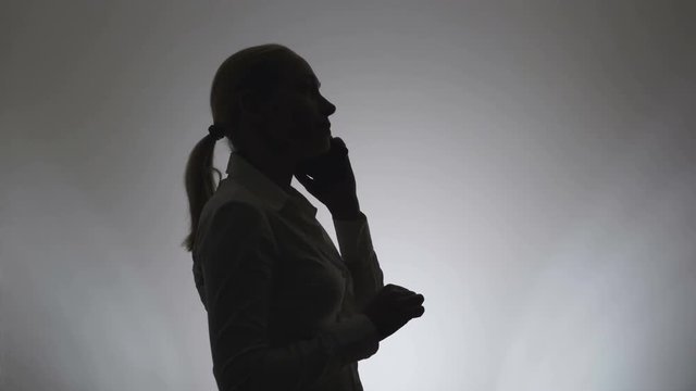 Silhouette of a woman on a white background. Portrait of a business woman silhouette talking on the phone